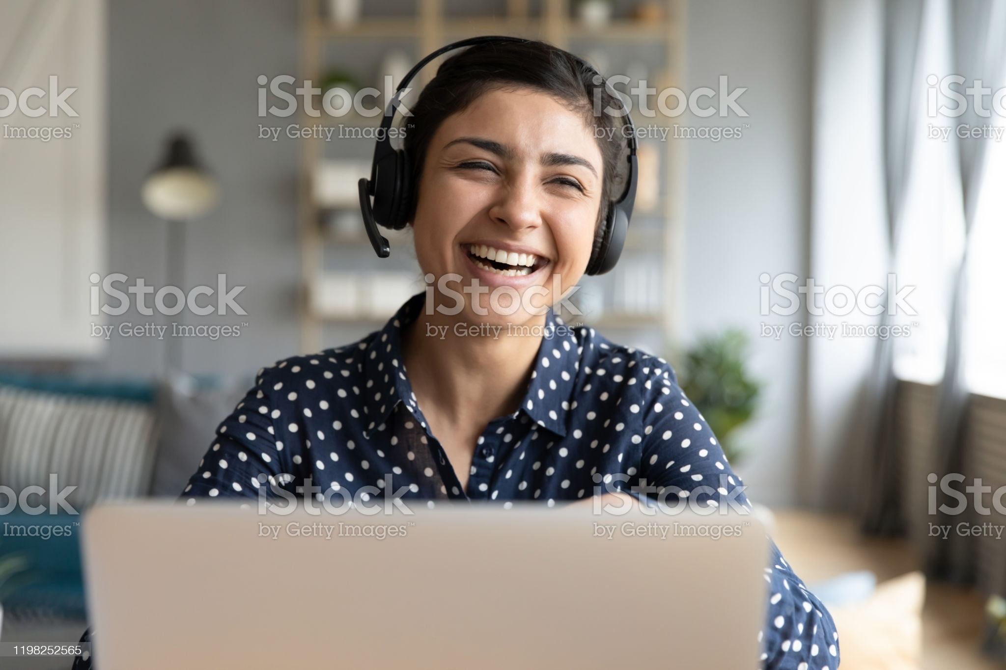 Cheerful indian woman wear headset laugh using laptop video stream conference call teach online, happy ethnic girl student gamer tutor have fun watch webinar web cam education entertainment concept